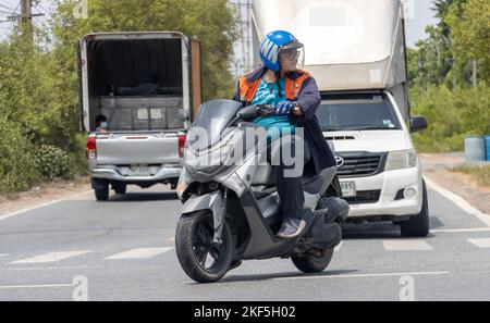 BANGKOK, THAILANDIA, 01 2022 GIUGNO, Un uomo su una moto entra in un incrocio trafficato Foto Stock