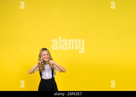 Ragazza scolastica adolescente con forbici, isolata su sfondo giallo. Creatività dei bambini, arti e mestieri. Foto Stock