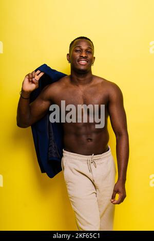 Ragazzo in tuta blu su sfondo giallo. Bell'uomo atletico in giacca sorridente Foto Stock
