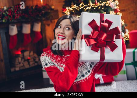 Foto di bella donna sognante mano tenere babbo natale dono guardare in su immaginare cosa all'interno pacchetto miracolo magia camera tempo casa al coperto Foto Stock