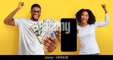 Coppia nera overjoyed che tiene i contanti molto e smartphone Foto Stock