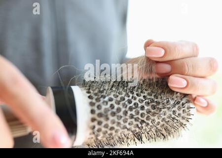 Le mani delle donne tengono il pettine con molti capelli. Problema di perdita dei capelli e concetto di salute dei capelli. Foto Stock