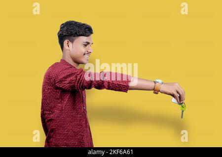 Uomo che tiene o che dà la chiave di casa sul diwali festival indiano isolato su sfondo giallo Foto Stock