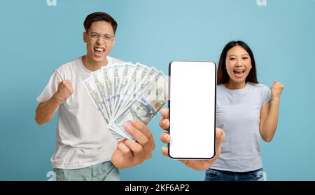 Coppia asiatica overjoyed che tiene i contanti molto e smartphone Foto Stock