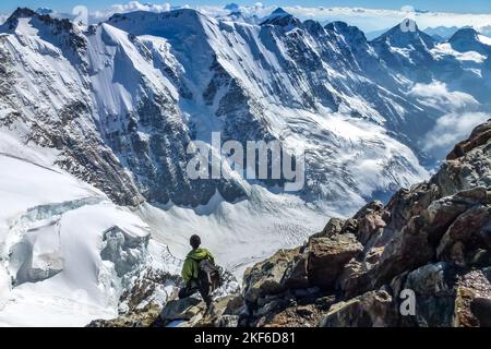 Descrizione: Alpinista su una scogliera rocciosa gode di una magnifica vista panoramica delle profondità del Rottal. Jungfrau-Höhenweg, Alpi Bernesi, Svizzera Foto Stock