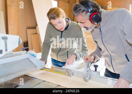 artigiano e falegname che lavorano come squadra per tagliare il legno Foto Stock