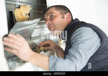 uomo che monta la piastra metallica sopra l'isolamento nella parete Foto Stock