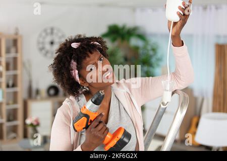 giovane donna che si sta esercitando sul soffitto con un trapano Foto Stock