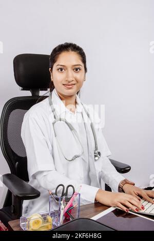 Un ritratto di una dottoressa sudasiatica seduta di fronte alla scrivania dell'ospedale Foto Stock
