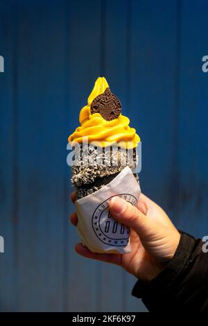 Gelato al frutto della passione di Mango in un cono nero per torta al camino al Good Food Coffee & Bakery, Praga, Repubblica Ceca Foto Stock