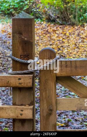 Un nuovo cancello in legno tenuto chiuso con corda in una riserva naturale. Concetto - chiuso, bloccato, chiuso, aperto, sigillato, sicurezza, accesso. Foto Stock