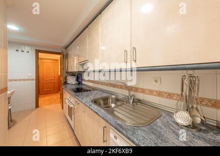 Cucina con armadi in legno color crema con ripiani blu e elettrodomestici bianchi da incasso Foto Stock