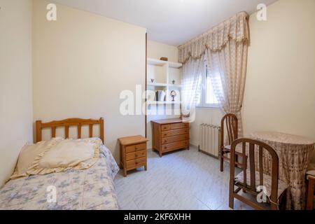 camera da letto con un piccolo letto matrimoniale con mobili in legno di pino color miele e un tavolo da letto con sedie abbinate Foto Stock