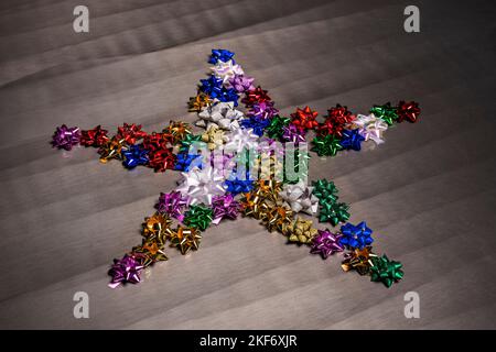 Stella colorata formata con stelle di carta da imballaggio su una trama grigio lucido Foto Stock