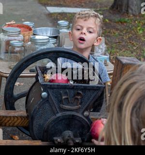 Detroit, Michigan - i bambini fanno sidro di mele con una pressa della mela ad un festival di caduta sul lato vicino orientale di Detroit. Foto Stock