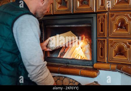 L'uomo che mette i tronchi di legno nel mantel casa Fire.Home dolce casa e inverno campagna vacanza idea immagine Foto Stock