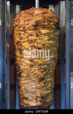 Griglia verticale con carne a strati per kebab o gyros, fast food per strada, focus selezionato Foto Stock