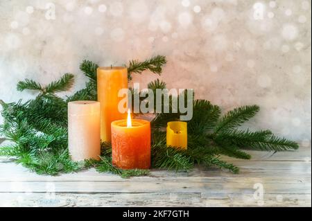 Primo Avvento, sistemazione con quattro candele in arancione e giallo, una è illuminata con una fiamma, rami di abete su legno rustico chiaro, bokeh fondo, copia s Foto Stock