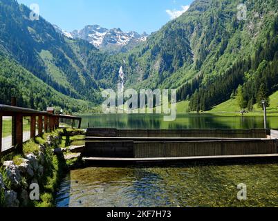 Paesaggio alpino panoramico con una cascata, un lago alpino trasparente e diversi stagni di allevamento di trote nelle Alpi austriache dello Schladming-Dachtein Foto Stock