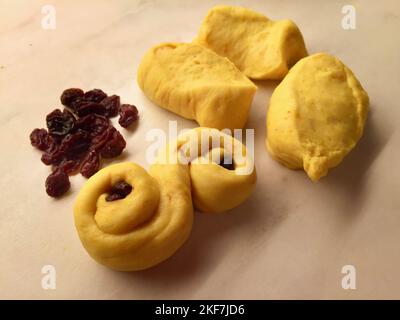 Pasta di zafferano e uvetta su un tavolo da forno per la cottura dei panini per le vacanze di dicembre. Foto Stock