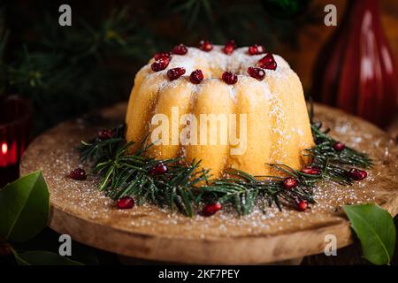 Torta Bundt decorata con glassa di zucchero e melograno in umore di Natale. Atmosfera Moody con candele e decorazioni. Capodanno. Dessert chiamato Foto Stock