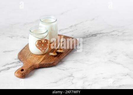 due bicchieri di yogurt sul piccolo tagliere decorativo in legno, concetto di coppia romantica colazione, spazio copia Foto Stock