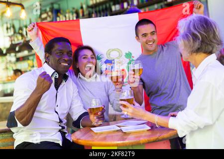 Amici felici che celebrano la vittoria della squadra peruviana nel bar della birra Foto Stock