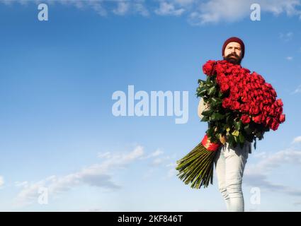 Uomo con bouquet di fiori di rose. Gay tiene un grande bouquet di rose rosse, proporre al fidanzato in data. Romantico ragazzo celebrare San Valentino. Foto Stock