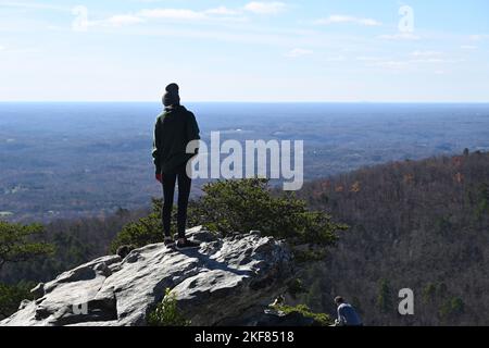 Un escursionista si trova sull'Hanging Rock Overlook ammirando la vista della regione piemontese del North Carolina in una fredda mattinata all'Hanging Rock state Park. Foto Stock