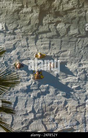 Volti di ceramici attaccati a una parete di stucco dell'artista di Santa Barbara Marge Dunlap. Foto Stock