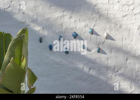 Volti di ceramici attaccati a una parete di stucco dell'artista di Santa Barbara Marge Dunlap. Foto Stock