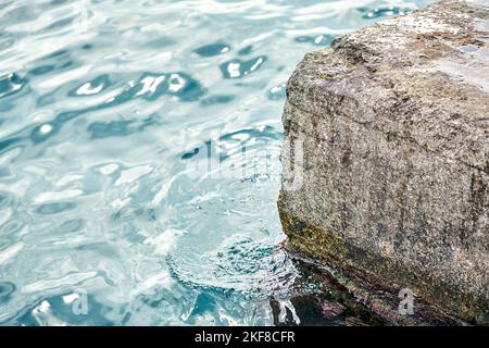 Molo di cemento grigio all'acqua di mare blu con piccole onde sotto la luce del sole brillante il giorno d'estate nel Porto Foto Stock