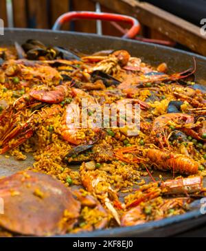 Delizioso, granchio gustoso, cozze, vongole, gamberetti, e altri ingredienti locali di pesce e verdure, in un ampio piatto di paella, essendo servito caldo ai visitatori di un e Foto Stock