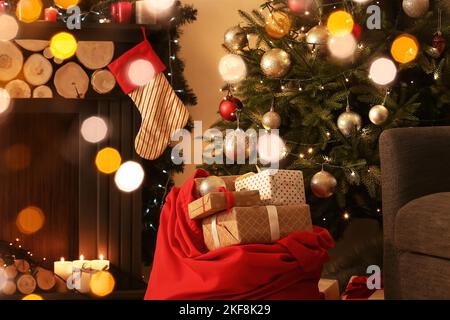 Babbo Natale pieno di regali sotto Natale in camera con caminetto Foto Stock