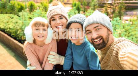 La famiglia felice tenendo selfie ad albero di Natale mercato Foto Stock