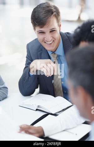 Portare nuove idee al tavolo. Un giovane uomo d'affari seduto in un incontro con i suoi colleghi. Foto Stock