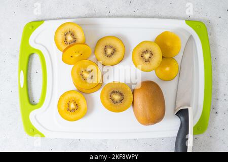 Fette di kiwi dorato dolce mature, primo piano sul tagliere, piatto Foto Stock