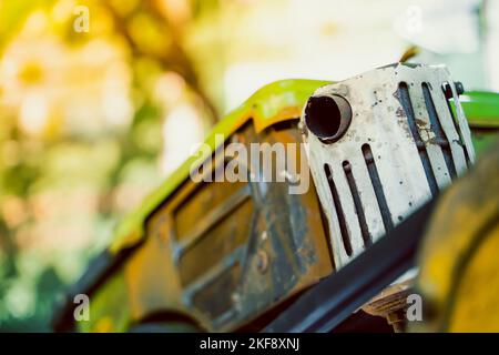 La marmitta del tubo di scarico di un trattore retrostante sullo sfondo di un piccolo motore diesel Foto Stock