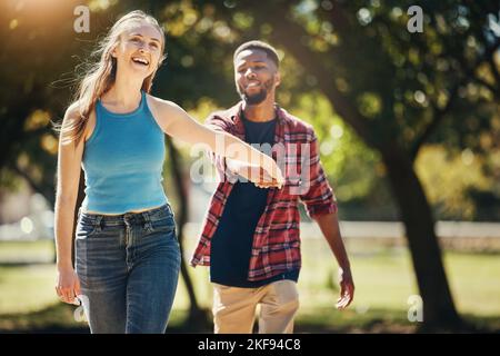 Amore, giardino e felice coppia tenendo le mani mentre camminano insieme in un appuntamento in un parco verde. Felicità, amore e interrazziale giovane uomo e donna Foto Stock