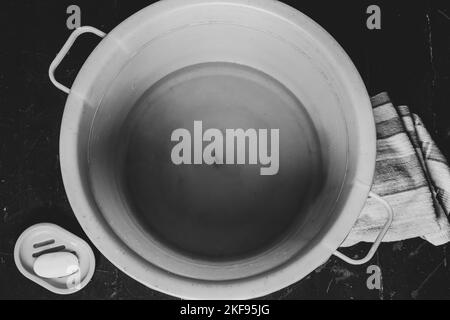 una ciotola di plastica con acqua saponata dopo il lavaggio dei piedi è sul pavimento vicino al sapone e ad un tovagliolo, una ciotola di acqua sul pavimento Foto Stock