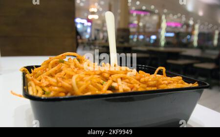 Spaghetti hakka speziati serviti in un contenitore da asporto monouso Foto Stock