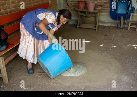 Fare ceramica di argilla rossa. Potter versando fuori l'argilla mescolata su una base di sabbia per asciugare per fare la ceramica di argilla rossa a San Marcos Tlapazola, Messico. È portatrice Foto Stock