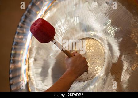 L'uomo che gioca il Gong sospeso durante la pratica spirituale Foto Stock