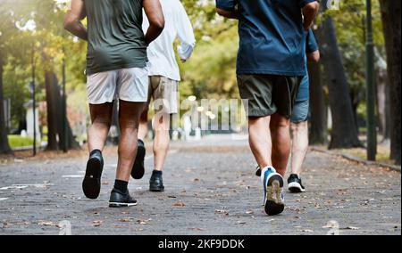 Fitness, uomini e club running nel parco, gambe tagliate in natura per l'esercizio sul percorso del giardino insieme. Motivazione, allenamento e amicizia, gruppo di Foto Stock