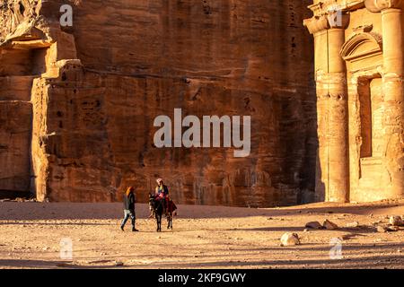 Petra, Giordania - 3 novembre 2022: Persone, asino al monastero di ad Deir nella città antica, vista panoramica al tramonto, sito patrimonio dell'umanità dell'UNESCO Foto Stock