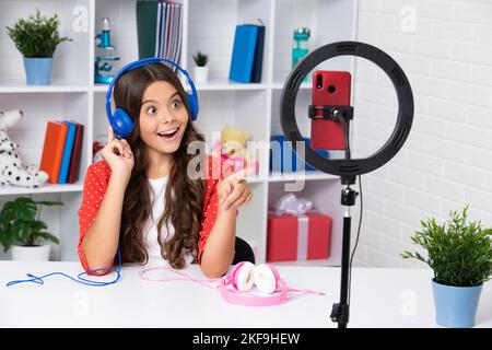 Teenager blogger fare video, bambino vlogger influenzencer contenuti record. Il blogger bambino registra video sul telefono mobile usando la lampada ad anello, le luci video per Foto Stock