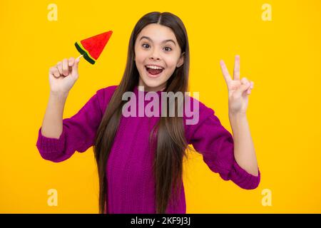 Faccia eccitata. Ragazza adolescente con caramelle al caramello su bastoni, zucchero dolce dipendenza. Bambino con lecca-lecca. Espressione stupita, allegra e felice. Foto Stock