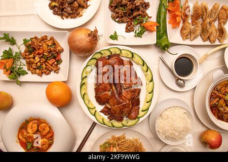Set di ricette cinesi asiatiche in piatti di porcellana bianca con gamberi piccanti, anatra arrosto, pollo alle mandorle, zuppa di miso, gyozas fritti, frutta e vegetab Foto Stock