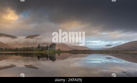 Scottish castello sul lato del lago. Bel riflesso delle nuvole rosse, grigie e bianche. Splendida immagine del paesaggio scozzese. Kilchurn Castello Foto Stock