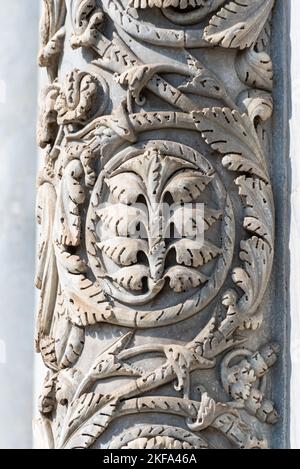 Primo piano sulle sculture floreali decorative scolpite su colonne di pietra della facciata esterna della chiesa cattolica italiana di Pisa Foto Stock